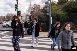 Bundled up against the cold, tourists walk through security fencing, which has been put up in a perimeter around the Capitol complex, Jan. 2, 2025, in Washington.