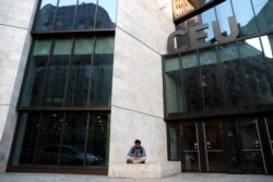 FILE - A man sits front of the building of the Central European University, a school founded by U.S. financier George Soros, in Budapest, Hungary, Apr. 9, 2018.