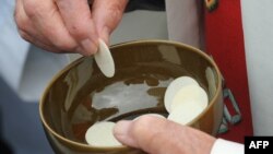 ARSIP - Seorang pendeta memegang roti komuni setelah Paus Benediktus XVI merayakan misa di La Prairie di Lourdes tanggal 14 September 2008 dalam perayaan penampakan Bunda Maria ke-150 kepada Bernadette Soubirous (foto: AFP Photo/Eric Cabanis)