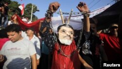 Seorang demonstran anti Presiden Mohamed Morsi mengenakan topeng Morsi dengan tangan yang dirantai dalam protes di depan Istana Presiden di Kairo (30/6). 