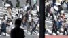 Seorang pria duduk di dekat jendela saat orang-orang yang memakai masker berjalan di sepanjang penyeberangan pejalan kaki di distrik Shibuya, 30 September 2021, di Tokyo. (Foto: AP)