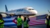 Pekerja di Bandara Internasional Jose Marti di Havana, Kuba, mengibarkan bendera AS dan Kuba menyambut penerbangan perdana maskapai Jet Blue dari Boston, AS, pada 10 November 2018. (Foto: AP/Desmond Boylan)