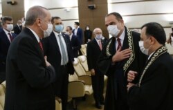FILE - Turkish President Recep Tayyip Erdogan, left, wearing a face mask to protect against the new coronavirus, and Basri Bagci, the new member of Turkey's Constitutional Court, greet each other during a ceremony, in Ankara, June 9, 2020.
