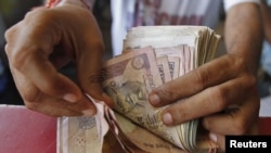 A grocery shop owner counts rupees notes in the western Indian city of Ahmedabad, May 23, 2012.