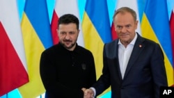 Polish Prime Minister Donald Tusk, right, welcomes Ukrainian President Volodymyr Zelenskyy after the two countries reached an agreement on exhuming Polish victims of WWII-era massacres by Ukrainian nationalists, in Warsaw, Poland, Jan. 15, 2025.