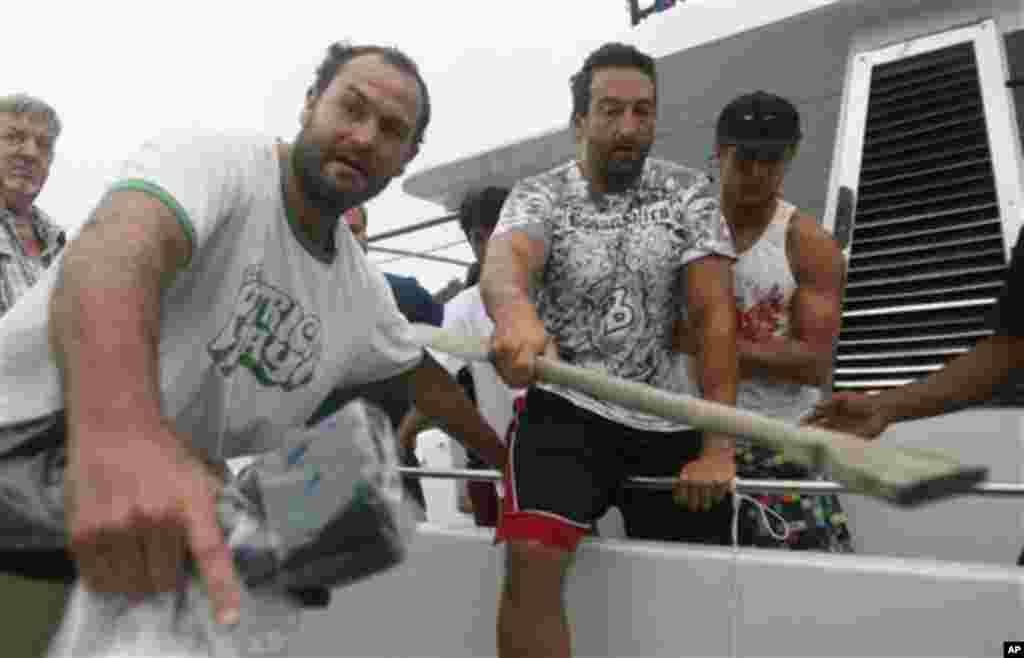 Australian tsunami survivor Richard Hope, left, assists his injured friend Robert Marino to disembark a boat upon their arrival at a port in Padang, West Sumatra, Indonesia, Wednesday, Oct. 27, 2010.