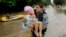 A member to the Texas Army National Guard carries Daniel Lopez to dry ground as people evacuate a neighborhood that was inundated after water was released from nearby Addicks Reservoir, Aug. 29, 2017, in Houston, Texas.