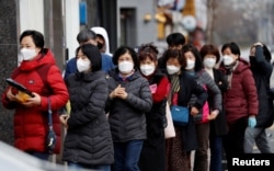 People wearing masks stand in a line to buy face masks in front of a drug store amid the rise in confirmed cases of the novel coronavirus disease of COVID-19 in Daegu, South Korea, March 3, 2020.
