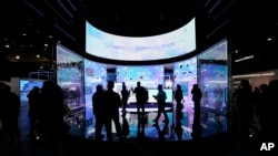 People look at a display of Samsung screens and products at the CES tech show Tuesday, Jan. 7, 2025, in Las Vegas. (AP Photo/Abbie Parr)