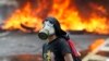 An anti-government protester stands in front of burning barricade on a highway in Caracas, Venezuela, April 24, 2017. 