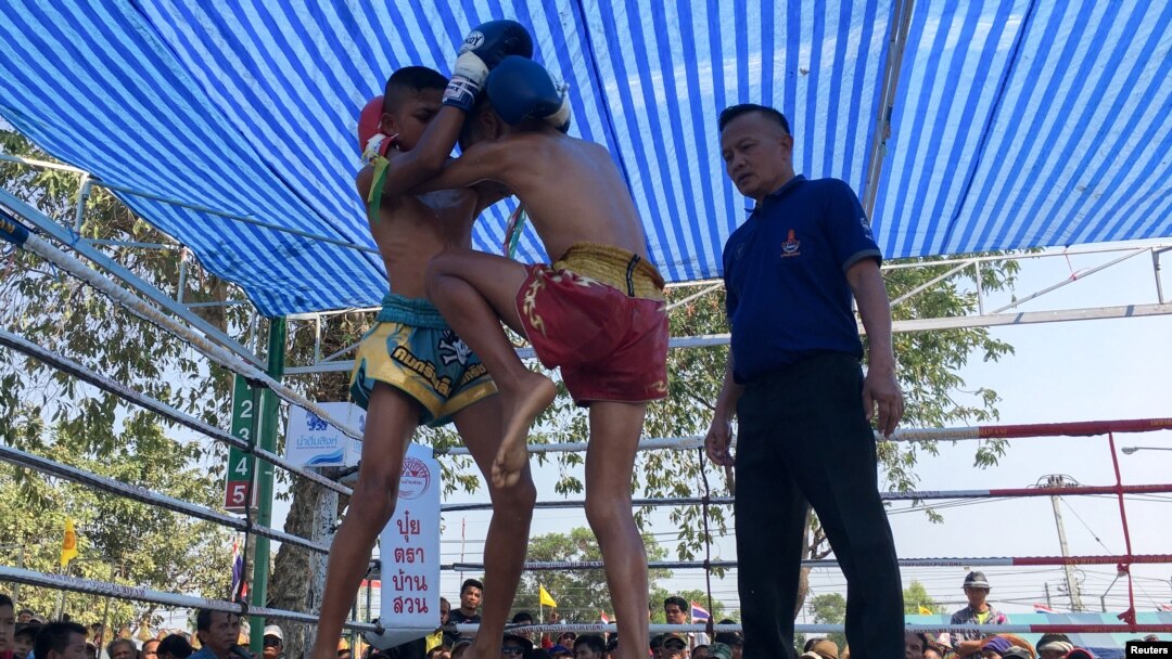 Nanthawat Pomsod (tengah), 11 tahun, seorang petinju anak, berlaga melawan Kritthonglek Sitkritthongkam (kiri), dalam pertandingan tinju di sebuah kuil, di Provinsi Buriram, Thailand, 2 Februari 2018. 