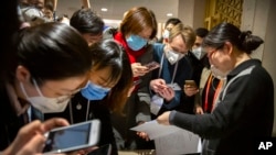 FILE - Journalists wearing face masks look at a Chinese government statement before an official press conference about the virus outbreak, at the State Council Information Office in Beijing, Jan. 26, 2020.