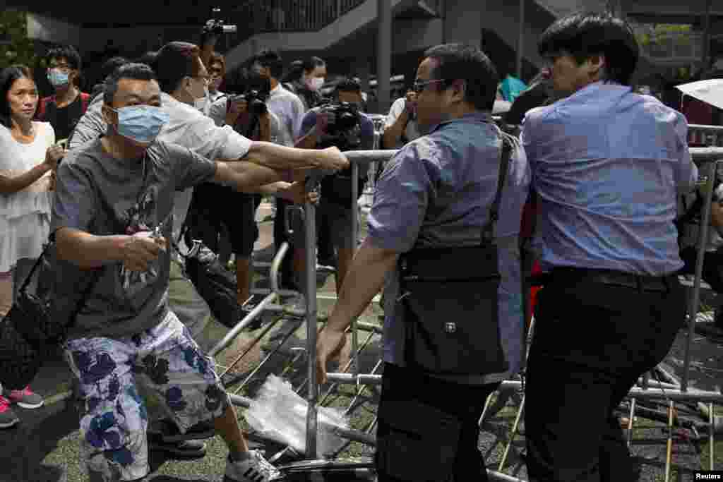 Un manifestant anti-occupation, à gauche, tient une pince alors qu&rsquo;il coupe le câble qui attachait les barricades que des pro-démocratie avaient érigées pour bloquer la route au centre de Hong Kong, le 13 octobre 2014. 