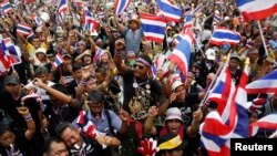 Demonstran anti-pemerintah melambaikan bendera dan meniup peluit sambil mendengarkan pemimpinnya berbicara di gedung Kementerian Keuangan yang mereka duduki di Bangkok (24/11). 