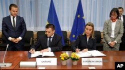 Menlu Ukraina Pavlo Klimkin (kiri) dan pejabat Uni Eropa Federica Mogherini menandatangani kesepakatan dalam pertemuan tingkat Menlu Uni Eropa di Brussels, Belgia, Senin (17/11).