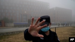 资料照片：世界卫生组织专家组抵达中国湖北省武汉市进行实地考察后，一名安保人员将记者从武汉病毒研究所附近驱离。(2021年2月3日)
