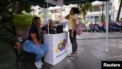 Dos mujeres venezolanas se registran como votantes para la próxima elección presidencial en una plaza de Caracas, el 19 de marzo de 2024.