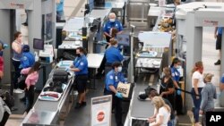 Personal del la Administración de Seguridad en el Transporte, TSA, procesan pasajeros en el aeropuerto internacional de Denver, Colorado, el 10 de junio de 2020.