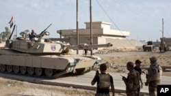Iraqi special forces soldiers use radio communication as a tank rolls down an alley in the village of Bazwaya, some 8 kilometers from the center of Mosul, Iraq, Oct. 31, 2016. 