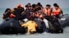 Migrants attempting to cross the English Channel to reach Britain get on an inflatable dinghy as the French police and gendarmes officers patrol on the beach of the Slack dunes in Wimereux, France.