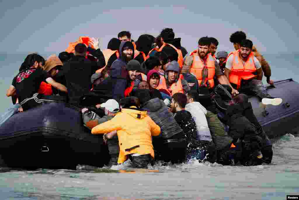 Migrants attempting to cross the English Channel to reach Britain get on an inflatable dinghy as the French police and gendarmes officers patrol on the beach of the Slack dunes in Wimereux, France. REUTERS/Benoit Tessier