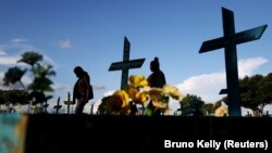 Dua wanita berjalan di samping makam orang yang meninggal akibat COVID-19 di pemakaman Parque Taruma di Manaus, Brazil, 20 Mei 2021. (Foto: REUTERS/Bruno Kelly)