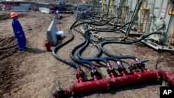 A worker helps monitor water pumping pressure and temperature, at a hydraulic fracturing and extraction site, outside Rifle, in western Colorado, March 29, 2013. 