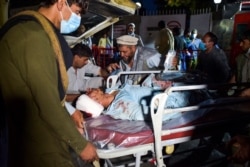 Medical and hospital staff bring an injured man on a stretcher for treatment after two blasts outside the airport in Kabul on Aug. 26, 2021.