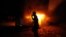 FILE - A Libyan civilian watches one of Ansar al-Shariah Brigades cars on fire, after hundreds of Libyans, Libyan Military, and Police raided the Brigades base, in Benghazi, Libya, Sept. 21, 2012. 