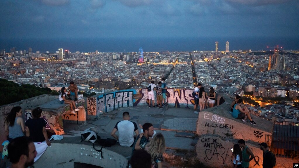 People gather outdoors at dusk on a viewpoint in Barcelona, Spain, Saturday, July 25, 2020. Britain is advising people not to travel to Spain and has removed the country from the list of safe places to visit following a surge of COVID-19 cases. (AP…