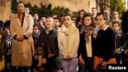 People pray and sing religious songs next to Notre Dame Cathedral after a fire broke out, in Paris, April 15, 2019. 