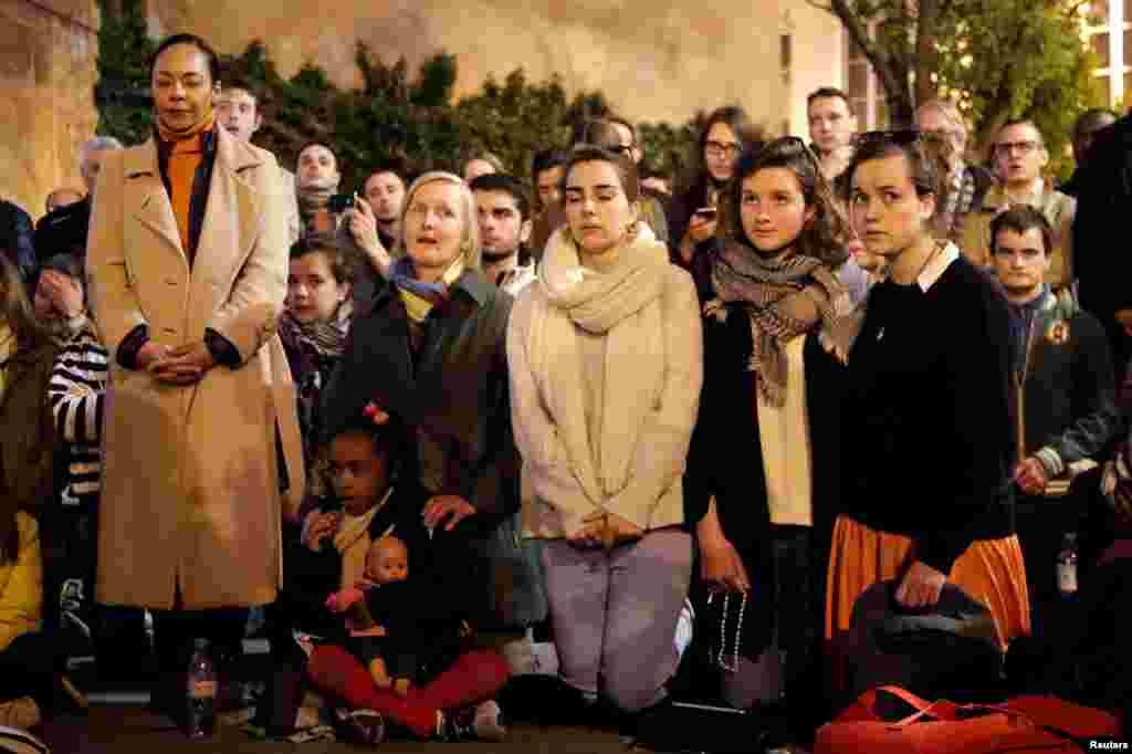 People pray and sing religious songs next to Notre Dame Cathedral after a fire broke out, in Paris, April 15, 2019. 