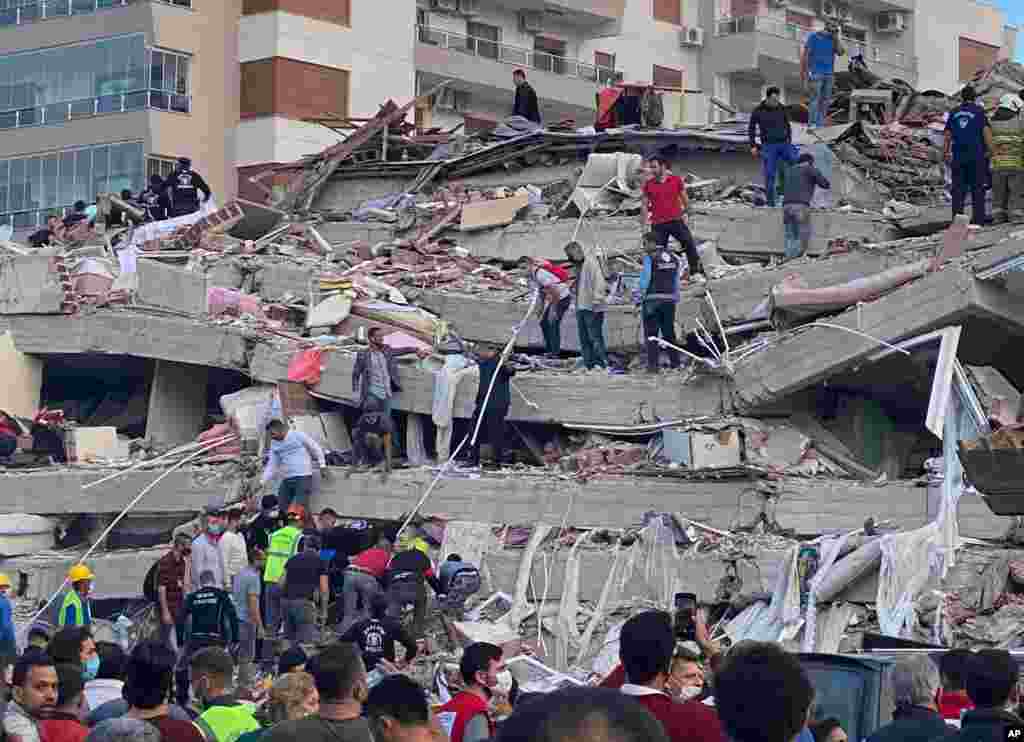 Rescue workers and local people try to save residents trapped in the debris of a collapsed building, in Izmir, Turkey, Oct. 30, 2020.