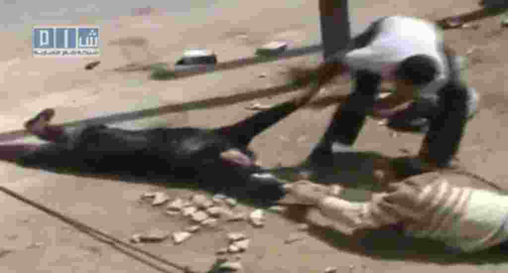 This amateur video image shot on April 24, 2011 and made available by SHAAM News Network and posted on youtube Thursday May 12, 2011 shows two men crawling close to the ground and dragging a woman to safety in Daraa, Syria. Several men in the city of Dara