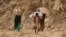 FILE - Yemenis carry relief supplies as they walk along a path outside the city of Taiz, Yemen, Jan. 17, 2016.