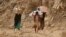 FILE - Yemenis carry relief supplies as they walk along a path outside the city of Taiz, Yemen, Jan. 17, 2016.