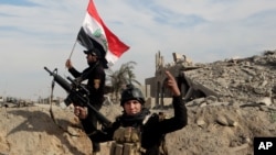 Iraqi security forces raise an Iraqi flag near the provincial council building in central Ramadi on Sunday.