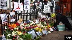 FILE —A supporter brings flowers to be placed beside other floral tributes, photographs and placards opposite the Russian Embassy in London on March 1, 2024, on the day of the funeral of Russian opposition leader Alexei Navalny.