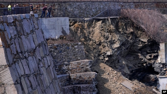 City officials and a private engineering group representatives look down at the destruction along the historic Cliff Walk on March 15, 2022 in Newport, Rhode Island. (AP Photo/Charles Krupa)