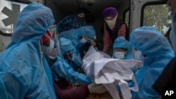 Relatives and volunteers in protective suits take out the body of a COVID-19 victim from an ambulance for cremation at a crematorium in Srinagar, Indian-controlled Kashmir, May 25, 2021. 