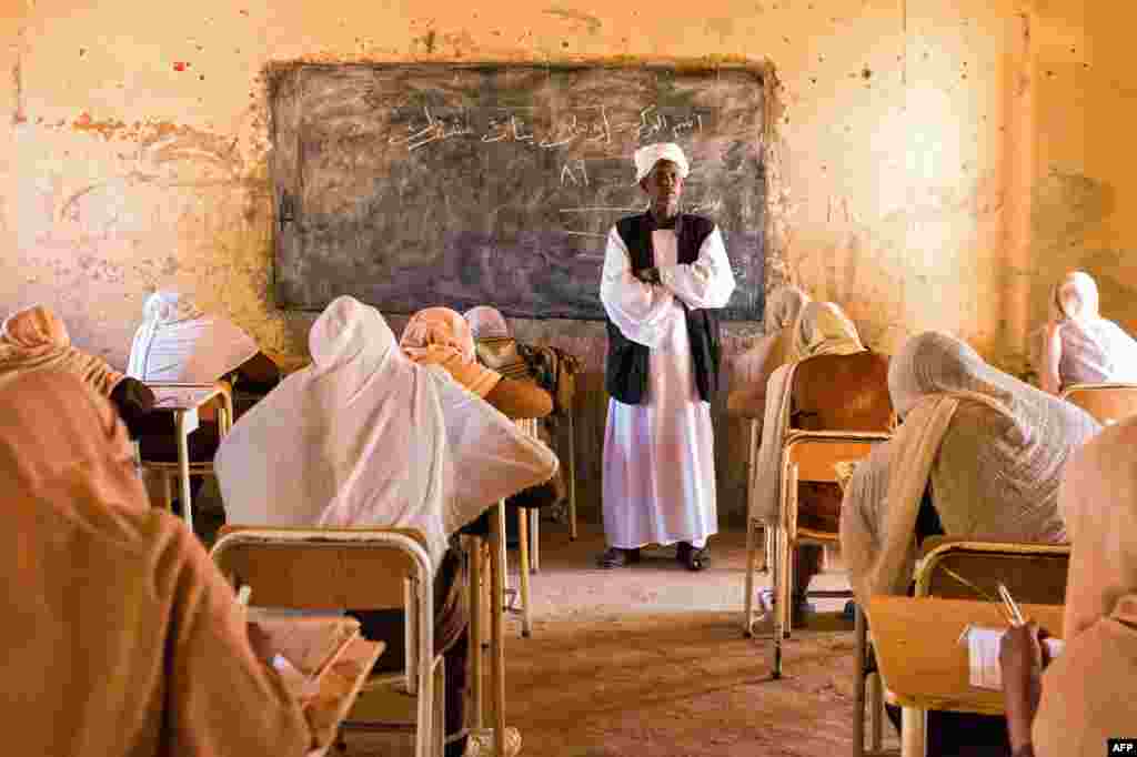 A teacher   watches implicit    mediate  schoolhouse  students during their end-of-year exams successful  the bluish   Sudanese colony   of Usli.