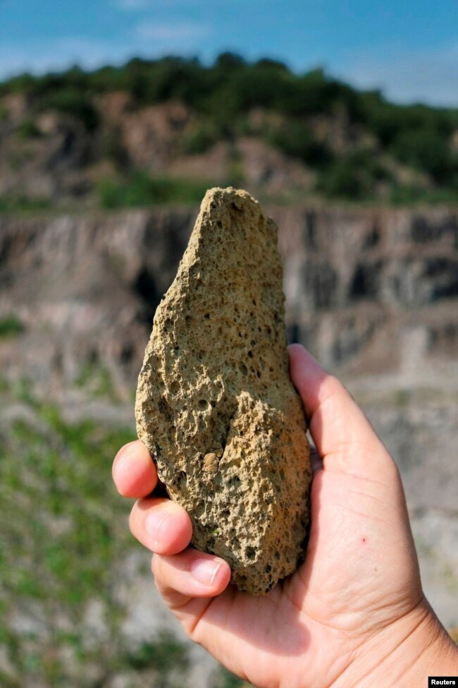 FILE - A person holds a heavily weathered artefact, a stone flake at the Korolevo I site in western Ukraine, Korolevo, Ukraine, August 23, 2023. (Roman Garba/Handout via REUTERS)