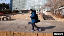 Park Gyung-sun checks his mobile phone on the way to a subway station as he delivers a parcel in Seoul, South Korea, Feb. 8, 2023.