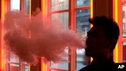 FILE - A patron exhales vapor from an e-cigarette at the Henley Vaporium in New York