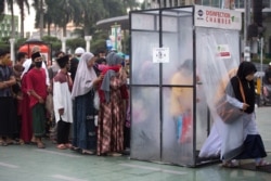 Muslims queue up to enter a disinfection chamber set up as a precaution against the new coronavirus outbreak, upon arrival for an Eid al-Adha prayer at Al Mashun Grand Mosque in Medan, North Sumatra, Indonesia, July 31, 2020.