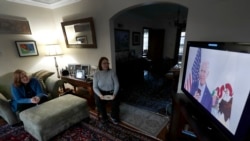 Lally Doerrer, right, and Katharine Hildebrand watch Joe Biden during his Illinois virtual town hall, in Doerrer's living room Friday, March 13, 2020, in Chicago. (AP Photo/Charles Rex Arbogast)