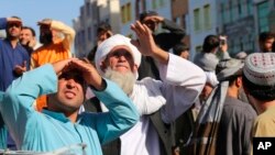 People look up at a dead body hanged by the Taliban from a crane in the main square of Herat city in western Afghanistan, on Sept. 25, 2021. 