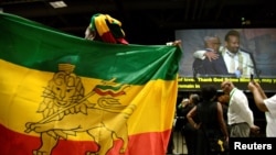 FILE - A member of the Ethiopian diaspora holds a national flag as Ethiopia's Prime Minister Abiy Ahmed (in white, on monitor) is hugged after calling on them to return, invest and support their native land, in Washington, July 28, 2018.