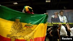 FILE - A member of the Ethiopian diaspora holds a national flag as Ethiopia's Prime Minister Abiy Ahmed (in white, on monitor) is hugged after calling on them to return, invest and support their native land, in Washington, July 28, 2018.