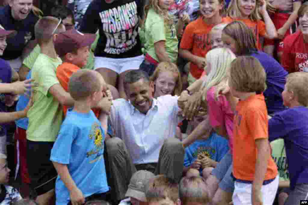 In this Aug. 15, 2011, photo, after posing for a photo kids from day camp help President Barack Obama to his feet in Chatfield, Minn. The surprise stop in came about after Obama trip director Marvin Nicholson, traveling at the front of the motorcade, radi